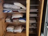 une armoire en bois remplie d'une multitude de vêtements et de couvertures