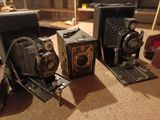 three old cameras sitting on a table in a room