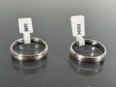 two silver rings with tags attached to them on a table