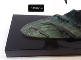a bronze sculpture of a shoe on a black stand