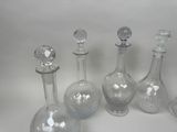 five glass bottles and a glass stopper on a white surface