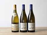 three bottles of wine are lined up on a wooden table