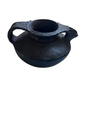 un petit pot noir muni d'une anse, sur fond blanc