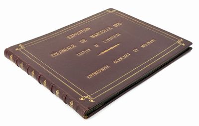 an old brown book with gold writing on it sitting on top of a white surface