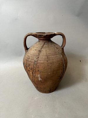 un vase brun posé sur une table à fond blanc