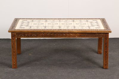 une photo d'une table en bois avec un plateau en carrelage, posée sur un tapis