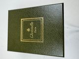 an old green book with a gold border on a white background