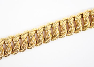 gros plan d'un bracelet en or sur une surface blanche