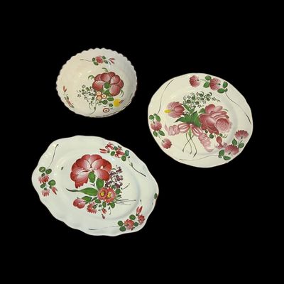 trois assiettes ornées de motifs floraux sur fond noir