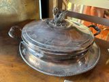 a silver plate with a bird on it on a wooden table