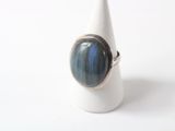 silver ring with a blue stone in the middle of it on a white cone