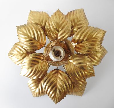 a gold flower with leaves on it on a white surface