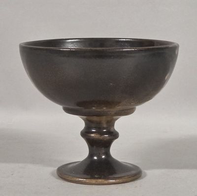 a black bowl sitting on a pedestal on a white surface