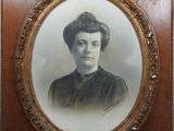 une vieille photo d'une femme en robe noire, dans un cadre en bois