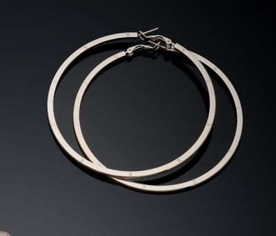 two silver hoop earrings on a black surface with a moon in the background