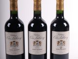 trois bouteilles de vin rouge sont alignées sur une surface blanche