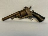 un vieux revolver avec une poignée en bois sur une surface blanche