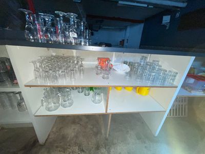 bottles and glasses on a shelf in a room with a lot of bottles