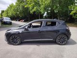 a black car parked in a parking lot with trees in the background