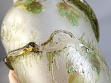 une main tenant un vase en verre orné d'une libellule
