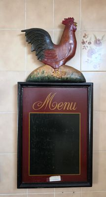 a rooster on top of a menu board in a restaurant