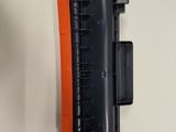 a close up of a black and orange toner on a white surface