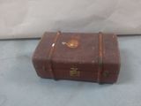 a small brown suitcase sitting on a white surface