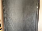 a bed with a sheet covering it in the corner of a room