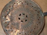 a silver plate with a metal handle on a table