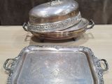 deux plateaux en argent et un plat à couvercle en argent posés sur une table en bois