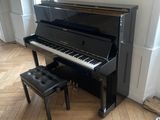 a piano in the corner of a room with a stool