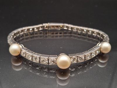 an image of a bracelet with pearls and diamonds on a table