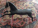 a wooden rocking horse on a rug in a living room