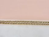 gros plan d'un bracelet en chaîne en or sur une surface blanche