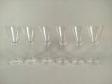 six verres à vin vides alignés sur une surface blanche