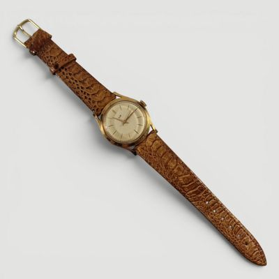 gros plan d'une montre sur une surface blanche avec un bracelet marron