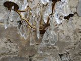 a chandelier hanging on a stone wall with a stone wall behind it