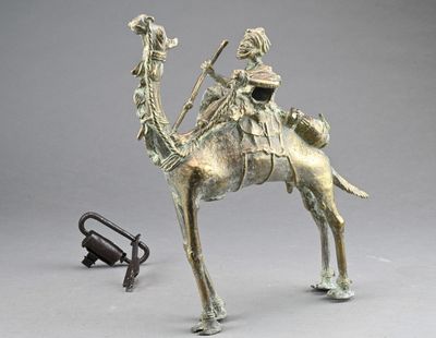 bronze statue of a man riding a camel with a bird on his back