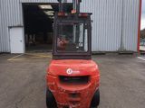 un chariot élévateur rouge garé devant un immeuble