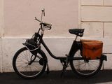 a bicycle with a basket on the back parked next to a building
