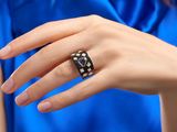 une femme en robe bleue tenant une bague en forme de dé noir et blanc