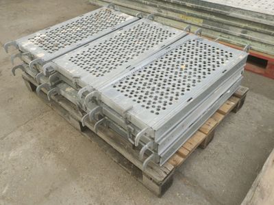 Plusieurs pièces métalliques sont empilées sur des palettes dans un entrepôt