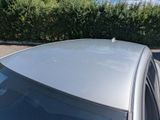 a silver car parked in a parking lot with bushes in the background