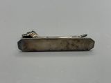 an image of a silver tie bar on a white surface