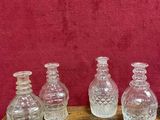 four clear glass vases sitting on top of a wooden table