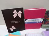 several notebooks are lined up on a white table with a pink bow