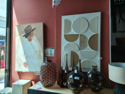 une table sur laquelle se trouvent des vases et un tableau, placée devant une fenêtre