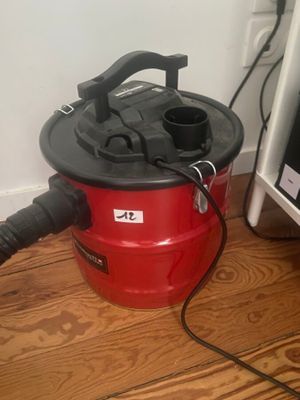 un aspirateur rouge posé par terre à côté d'une télévision