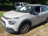 La voiture est garée dans l'herbe, près des arbres.