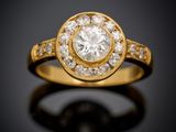 une bague en or jaune sertie d'un diamant rond entouré de petits diamants